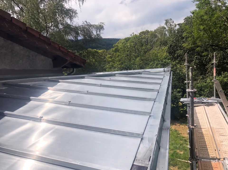 Vue aérienne d'une maison de plain-pied avec extension, enduit blanc, toiture en tuiles canal terre cuite, deux fenêtres de toit type Velux avec volet roulant