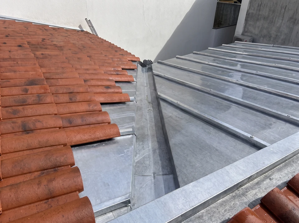 Deux couvreurs-plombiers travaillent en toiture, par temps ensoleillé